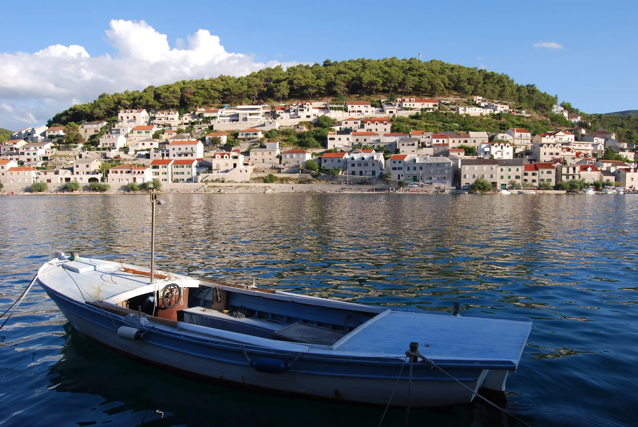 Weiße Steinhäuser und ein traditionelles Boot im Hafen von Pučišća auf Brač